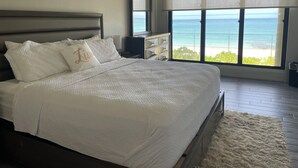A large bed with white bedding, a headboard, and a pillow with the word "Live". - Leisure Daze by the Sea (Frederiksted)