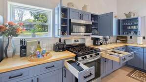 A modern kitchen with a built-in microwave, gas stove, and open shelving. - Country Cottage by the Salmon River - 3BR, Sleeps 8, Deck & Firepit. (Richland)