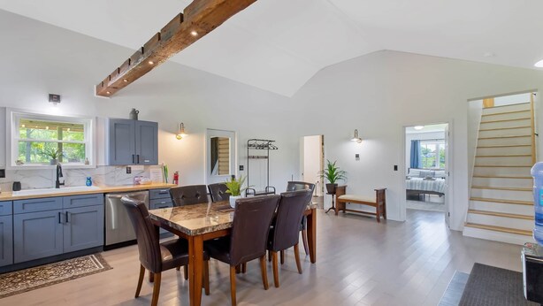 A spacious kitchen with a dining area, wooden beams, and a view to a balcony. - Country Cottage by the Salmon River - 3BR, Sleeps 8, Deck & Firepit. (Richland)