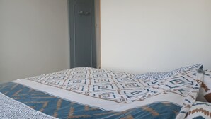 A bedroom with a bed, a door, and a wall-mounted artwork.