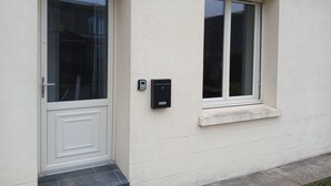 A building with a white exterior, a door with a glass panel, and a window with a small ledge.