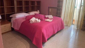 A bedroom with a large bed, pink bedding, a wooden headboard, and a window with sheer curtains. - RoMi's House cozy facility in the hills of the Castelli Romani. (Lazio)