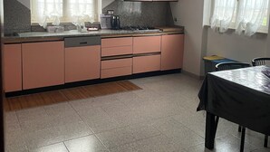 Eine Küche mit rosa Schränken, einem Herd und einem Fenster mit transparenten Vorhängen.