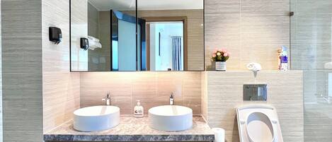 A modern bathroom with two sinks, a toilet, and a large mirror.
