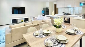 A modern living room with a dining area, a flat-screen TV, a sofa, and a kitchen in the background. - 2BR Apartment in Westlands,Nairobi|GTC|13th Floor (Nairobi)