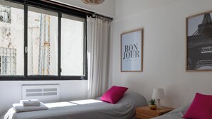 A hotel room with two beds, a window with curtains, a wall-mounted sign, and a framed picture. - MOT Anchorena 1400 (Buenos Aires)