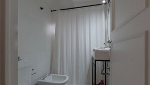 Une petite salle de bain propre, équipée de toilettes, d’un bidet et d’un lavabo.