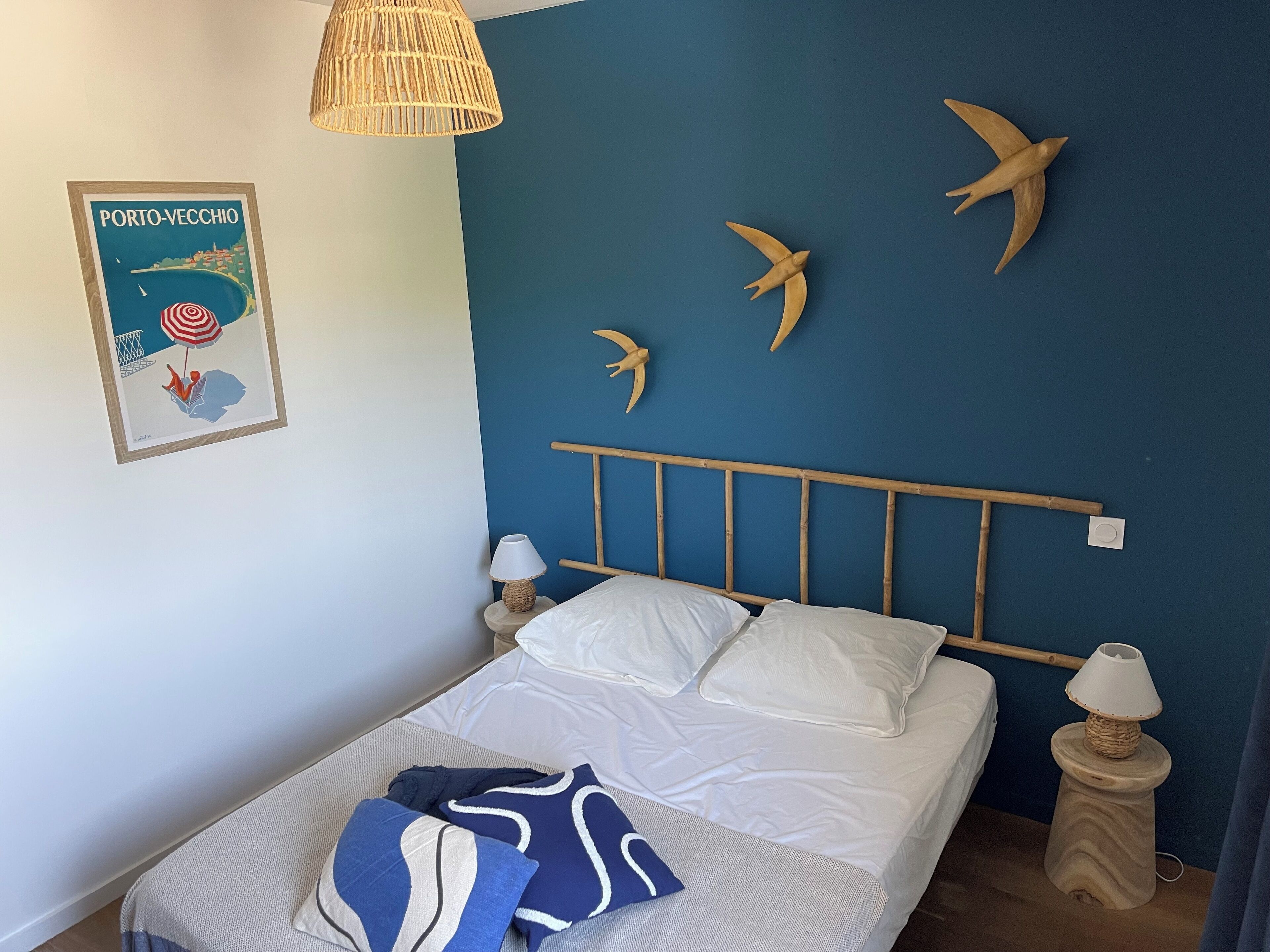 A bedroom with a bed, pillows, a wall poster, and wooden bird decorations.