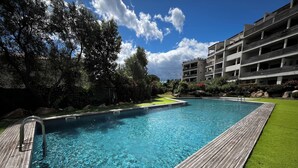 Ein klares Schwimmbecken mit Holzterrasse und Rasenfläche.