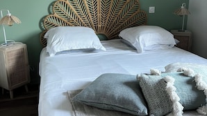Ein Bett mit einem Kopfstück im Blattmuster, weißer Bettwäsche und zwei Nachttischlampen.