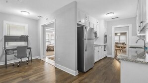 A modern kitchen with white cabinets, a stainless steel refrigerator, and a granite countertop. - Charming Historic house 10 minutes from Downtown FW and Stock yards (Fort Worth)