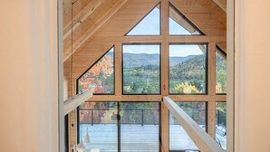 A room with large windows offering a view of a forested landscape. - Harfång - Spectacular view of Mount Edward (L'Anse-Saint-Jean)