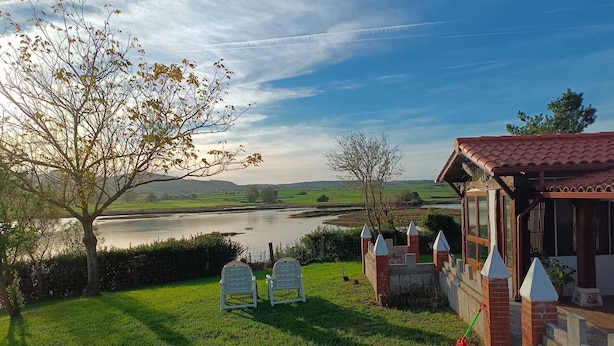 Vista al río con un pabellón, sillas y un césped.