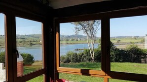 Una habitación con amplios ventanales que ofrecen vistas a un lago y la campiña circundante.