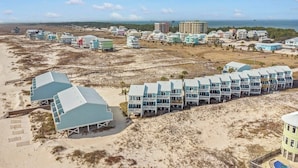 Un hotel frente a la playa con varios edificios de techos azules, una playa de arena y una vista despejada del océano.