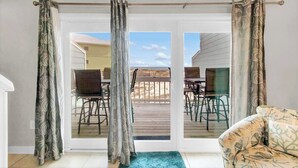 Una habitación con puerta corrediza de vidrio que da a un patio al aire libre con mesa y sillas.