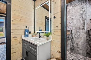 Un baño con paredes de madera, un lavamanos blanco y una salpicadura de mármol.