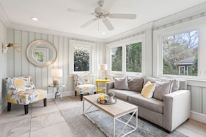 A living room with a sofa, armchairs, a coffee table, a ceiling fan, and large windows. - Patios, Beach Gear, Walk to beach (Virginia Beach)