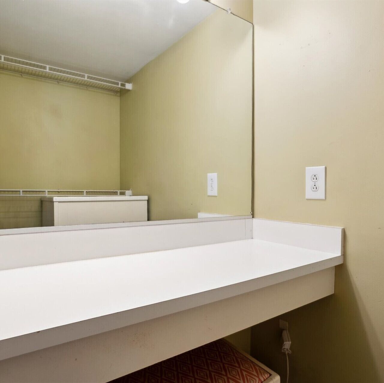 A bathroom with a white sink, mirror, and beige walls.