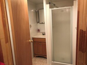 A bathroom with a wooden vanity, a sink, a mirror, and a frosted glass shower door. - Cozy Lakeside Escape on Lake Pleasant. (Lake Pleasant)