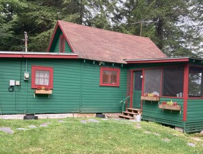 A green wooden house with a red roof, a front porch, and a small deck area. - Cozy Lakeside Escape on Lake Pleasant. (Lake Pleasant)