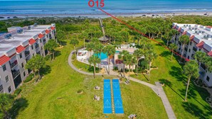 Een resort met een zwembad, palmbomen en uitzicht op het strand.
