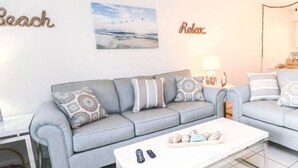 Een woonkamer met een grijze bank, een witte salontafel en een lamp.