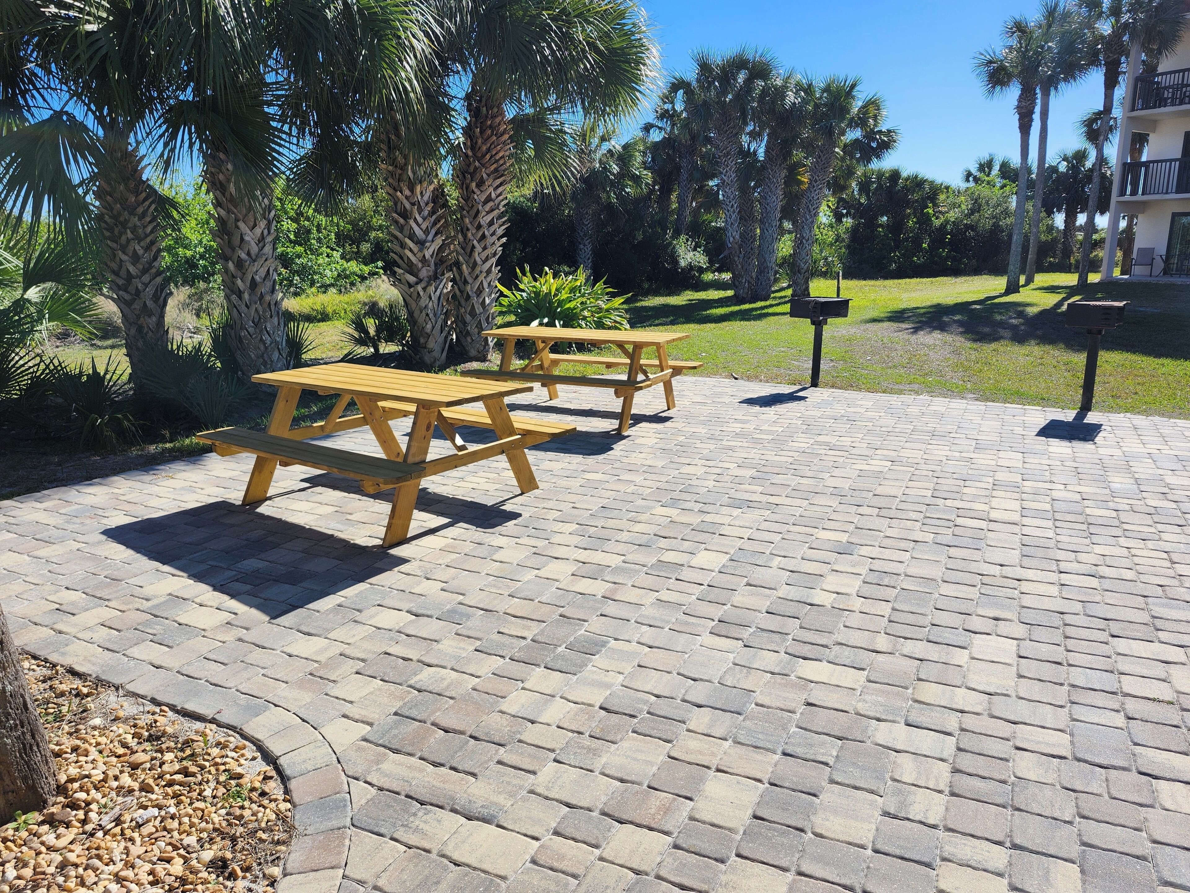 Un patio empedrado con mesas de picnic de madera y un buzón.