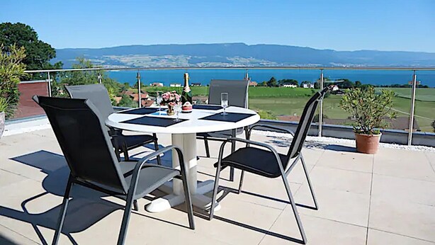 A round table with four chairs on a terrace overlooking a body of water and distant hills. - Chalet ideal for relaxing, with breathtaking lake and mountain views (Châtillon)