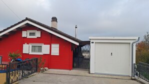 A red house with a white garage door and a small shed. - Chalet ideal for relaxing, with breathtaking lake and mountain views (Châtillon)