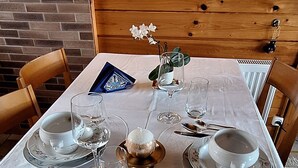 A dining table set with plates, cutlery, and glasses, with a brick wall and wooden paneling in the background. - Chalet ideal for relaxing, with breathtaking lake and mountain views (Châtillon)