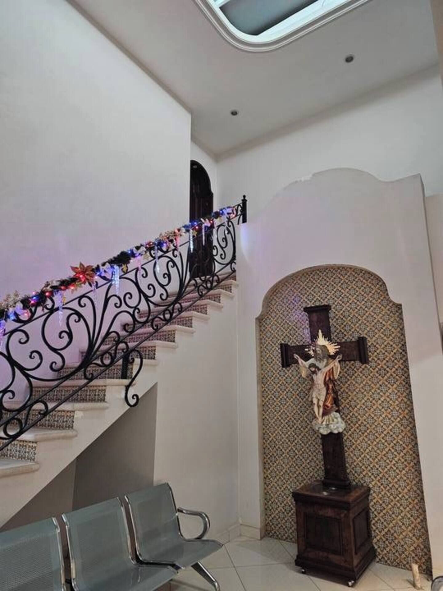 A staircase with a decorative railing, a religious statue, and a patterned wall.