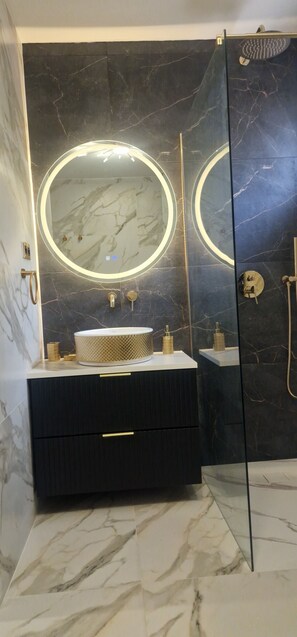 A modern bathroom with a marble vanity, a round mirror, and a glass shower enclosure. - Casa Ghjulia ★★★★ - Luxury & Relaxation in Porto-Vecchio (Porto-Vecchio)