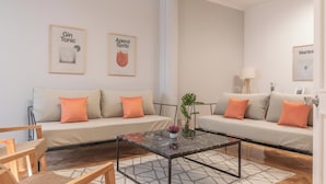 Uma sala de estar moderna com dois sofás, uma mesa de centro e quadros nas paredes.
