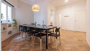 Uma área de refeições com piso de madeira em padrão herringbone, uma mesa de jantar preta e cadeiras pretas.