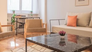 Uma sala de estar moderna com sofá, mesa de centro e área de jantar com mesa e cadeiras.