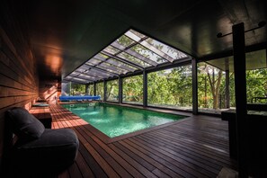A modern indoor swimming pool with wooden decking and large windows. - Quinta dos Carqueijais Resort & Wellness (Terras de Bouro)