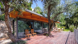 Terraza de madera con mobiliario exterior y cerramiento de vidrio.