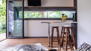 Una cocina moderna con puerta de vidrio, taburetes de madera y televisor montado.