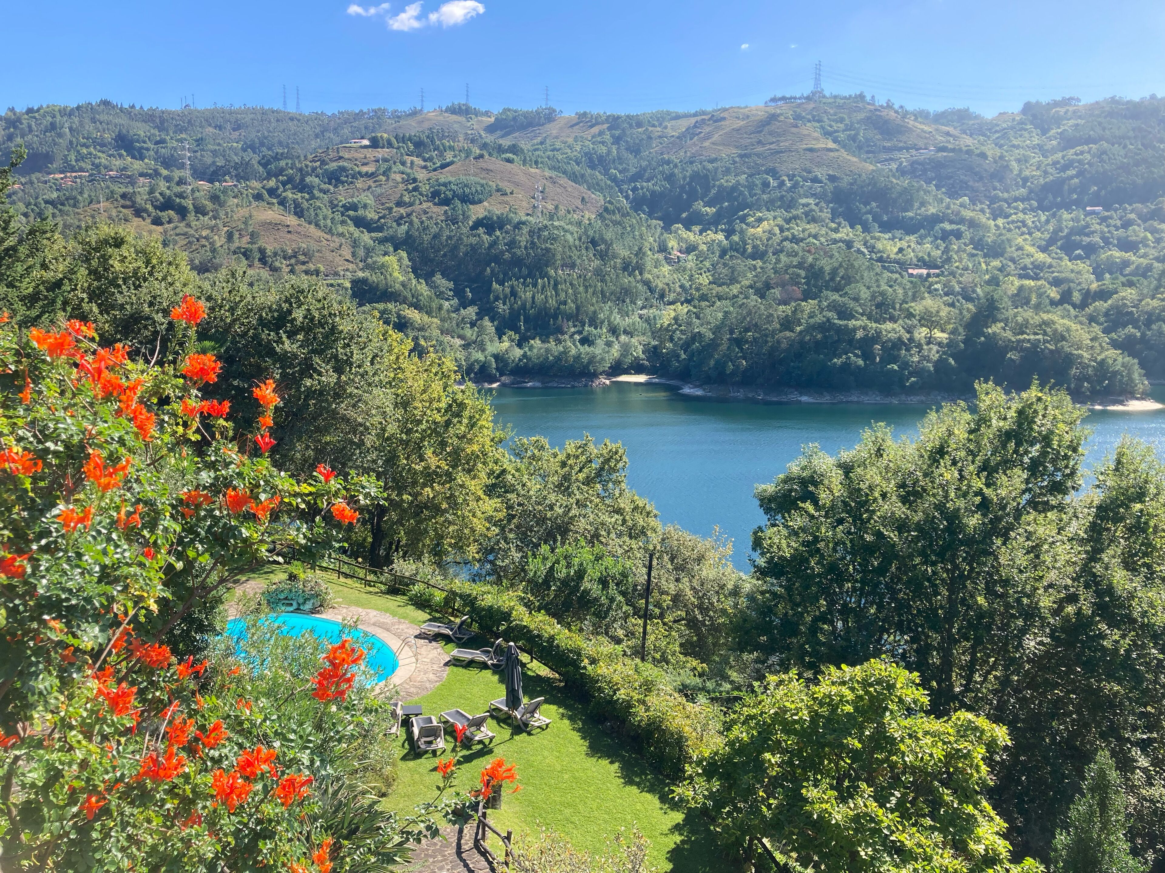 Un espace piscine avec des chaises longues et une vue dégagée sur un lac entouré de collines.