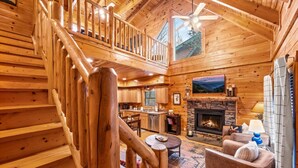 Ein Holzblockhaus im Inneren mit Treppe, Wohnzimmer, Kamin und Küche.