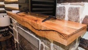 Una barra de madera con un televisor montado, frente a una pared de piedra.