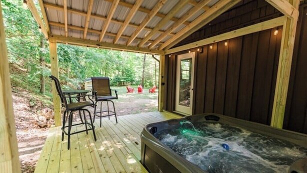 Una terraza de madera con un jacuzzi, una mesa y sillas.