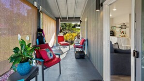 A covered outdoor seating area with red chairs, a blue pot with a plant, and a view into a kitchen area.