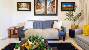 A living room with a grey sofa, a small side table with books, a coffee table with plants, and three framed pictures on the wall. - Ocean Sol Historic Old San Juan (San Juan)