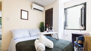 A bedroom with a bed, a desk, a chair, an air conditioner, a window, and a mirror. - Ocean Sol Historic Old San Juan (San Juan)