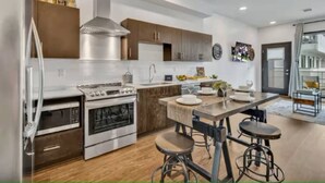 Una cocina moderna con electrodomésticos de acero inoxidable, armarios de madera y una isla central con taburetes.
