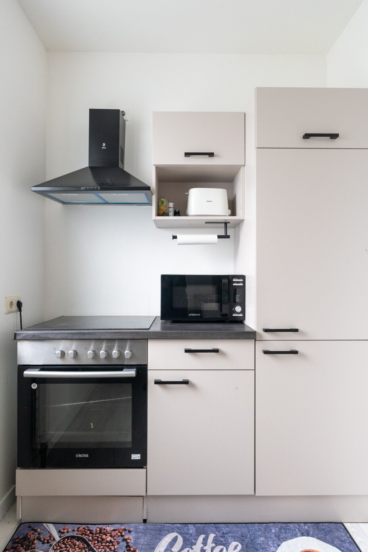 Een koelkast, een oven, een kookplaat, kookgerei, borden en bestek