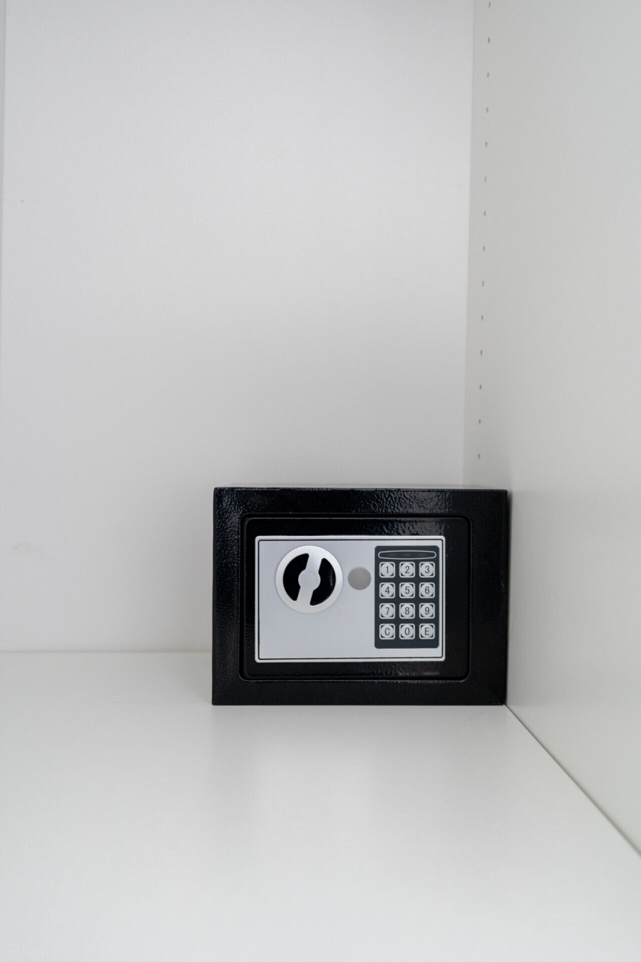 A black and silver electronic keypad lock on a white wall.