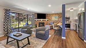 Una sala de estar moderna con chimenea, comedor y cocina equipada con electrodomésticos de acero inoxidable.